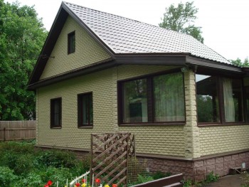 Деревянный дом, облицованный светлой плиткой «под кирпич»