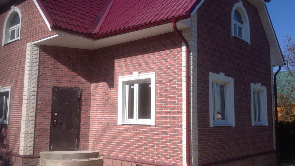 Деревянный дом, облицованный красной пестрой плиткой